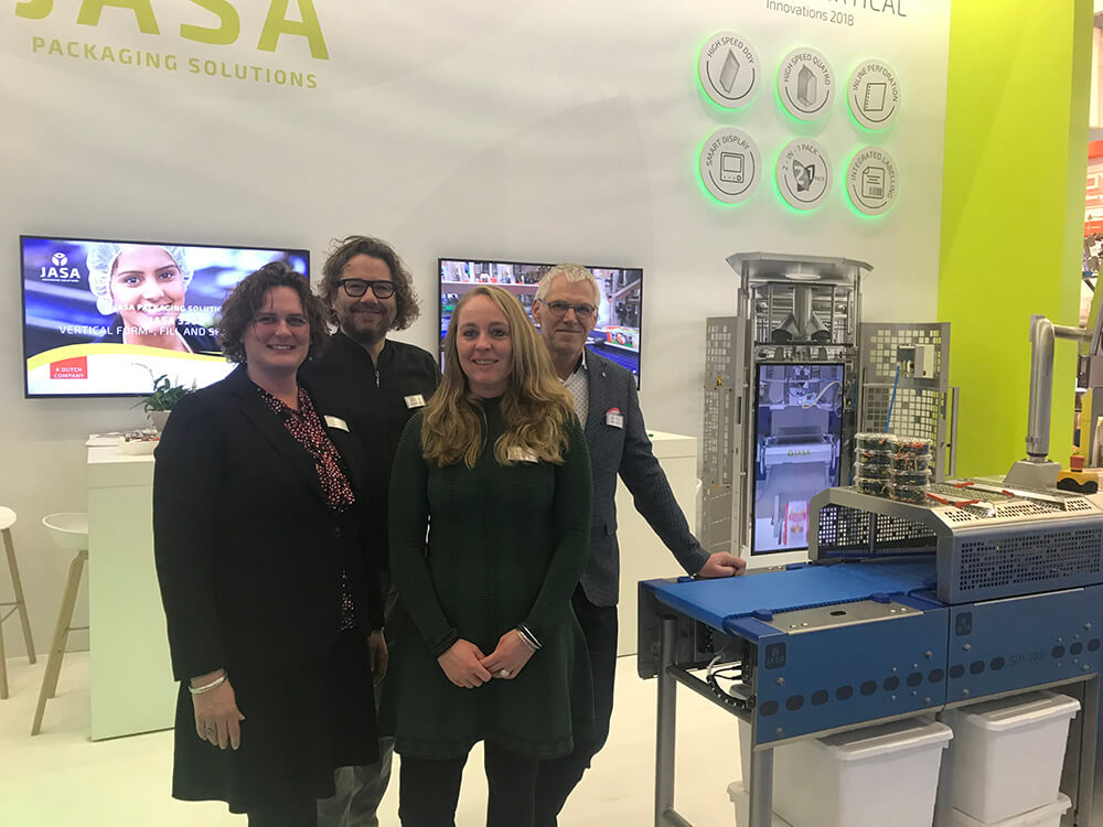 Four colleagues from JASA stood in front of their stand at an exhibition.